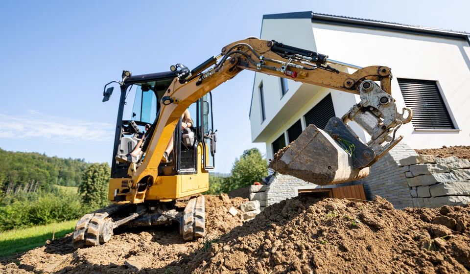 Chantier extérieur avec pelleteuse-chargeuse jaune en activité sur terrain de construction